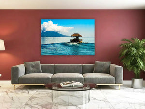 Tableau déco mer et plage représentant un paysage tropical aux eaux turquoise, présenté au-dessus d'un canapé dans un salon contemporain.