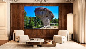 modern living room with beige chairs, marble coffee table, and large wall art of mushroom-shaped rock formation