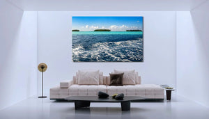 Modern living room with beige sofa, black coffee table, and large ocean island wall art
