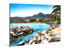 Acrylic photo print featuring a coastal landscape with blue sea, rocky shore, palm trees, and distant hills.