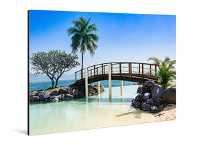 Acrylic photo print featuring a tropical beach scene with a wooden bridge, palm trees, and clear water.