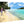 Acrylic photo print showing people walking on a tropical beach with palm trees and turquoise water