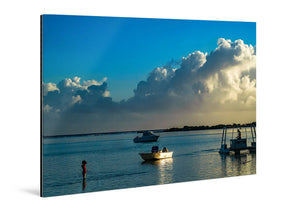 Acrylic photo print of serene beach scene with boats, child in water, and dramatic sky.