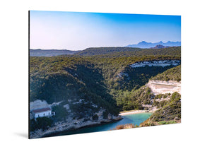 Glossy aluminum wall art print featuring a scenic landscape with lush green hills, a small bay, and a distant house.