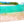 Tableau aluminium représentant un lagon turquoise, une plage de sable rosé et des cocotiers sous un ciel lumineux