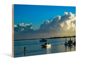 Photo print on wood featuring a serene beach sunset, boats, and clouds over calm water.