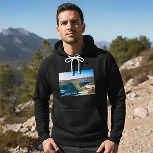 Man outdoors wearing black hoodie with landscape photo print, mountains and trees in background