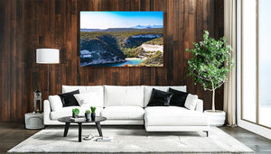 Modern living room with white sofa, wood panel wall, landscape art print, and indoor plant