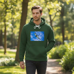 Man in green hoodie with flying bird art print, walking in a sunlit park
