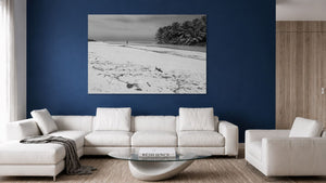 Tableau mural noir et blanc représentant une plage tropicale paisible, bordée de palmiers, avec une silhouette solitaire face à la mer