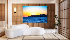 Modern living room with framed ocean sunset art print, minimalist sofa, and bonsai tree