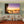 Modern living room with beige sofas, orange rug, and large sunset beach photo wall art.