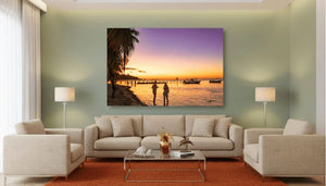 Modern living room with beige sofas, orange rug, and large sunset beach photo wall art.