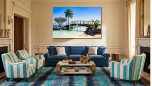 Elegant living room with blue velvet sofa, striped armchairs, and tropical bridge wall art