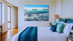 Modern bedroom with large ocean photography wall art above bed, teal and white decor
