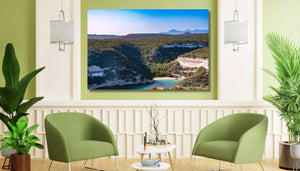Modern living room with green chairs, wall art landscape of river and lush hills, indoor plants