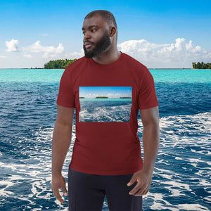 Man in red t-shirt with ocean photo print, standing by tropical turquoise sea
